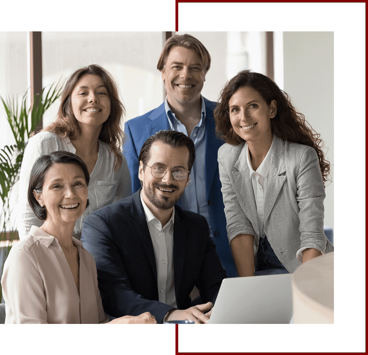 Smiling group of professionals around laptop.