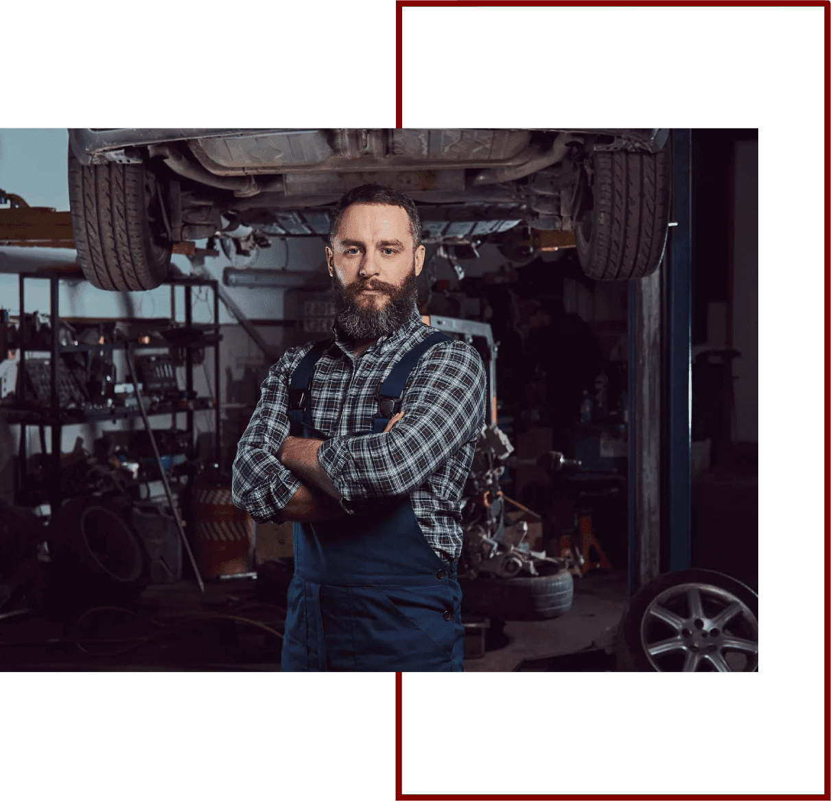 Mechanic standing under lifted car in garage.